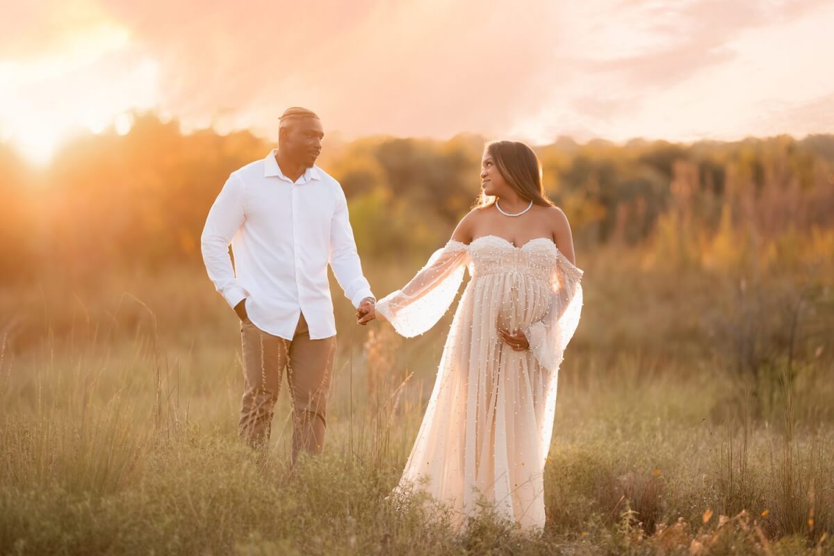 Expecting couple standing in a golden field at sunset during a babymoon maternity session near Austin