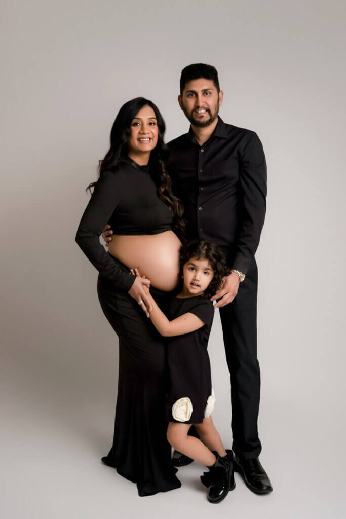 Family of three in black outfits posing together during a maternity photo session near Round Rock, Texas