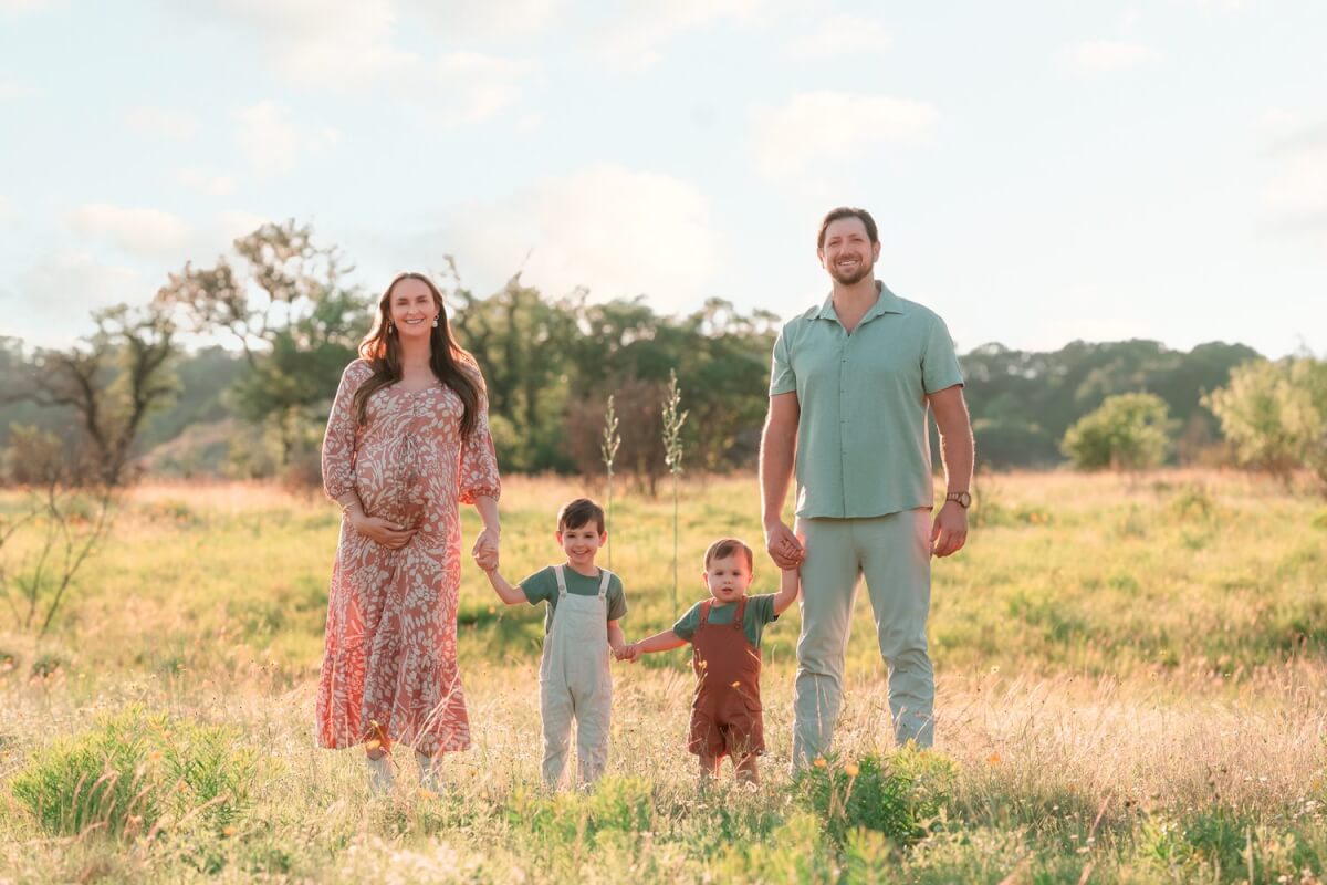 Expecting family in a golden field near Leander, Texas during an outdoor maternity session