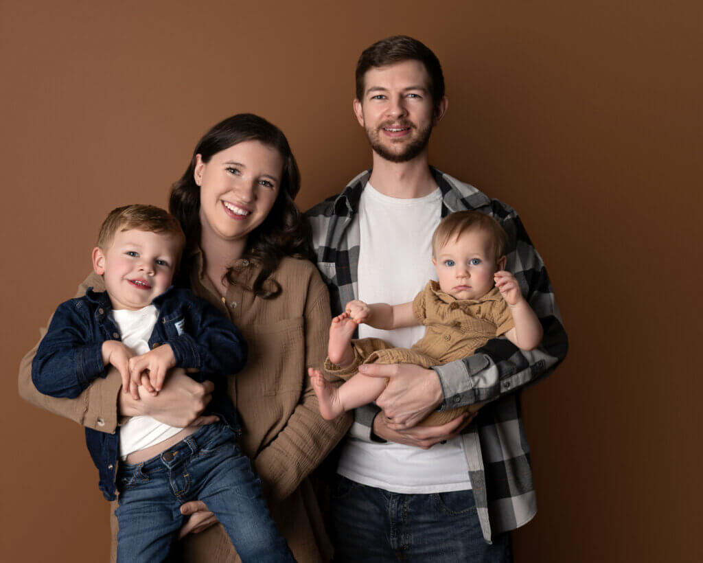Family in coordinated neutrals on a brown studio backdrop in Leander, Texas